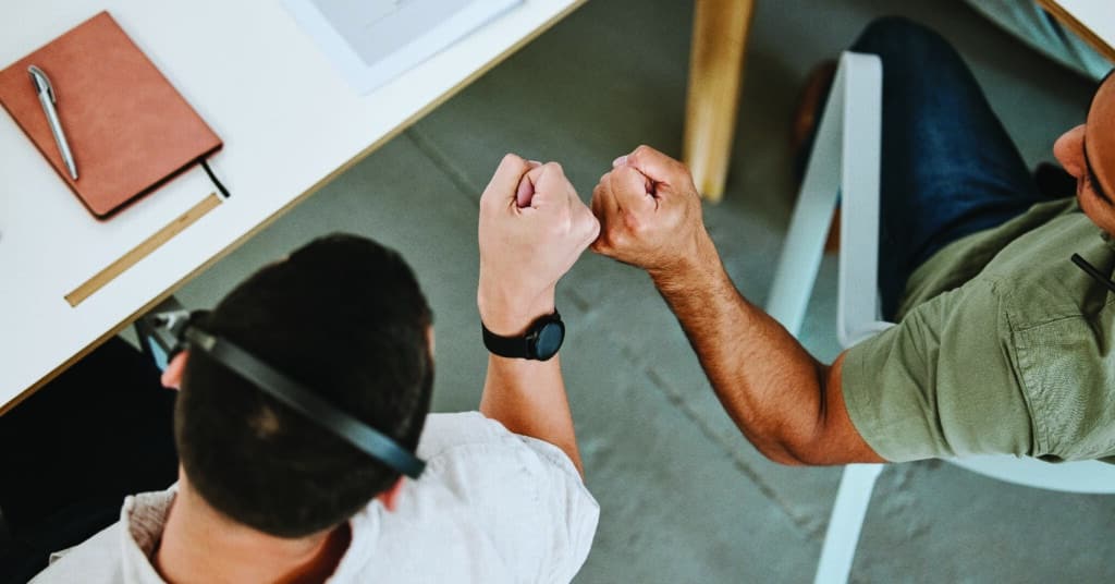 Two Sales People Giving Eachother Fist Bumps